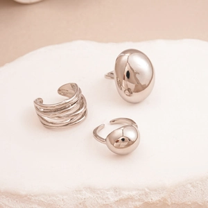 Detailed view of polished silver geometric rings on a natural white stone surface