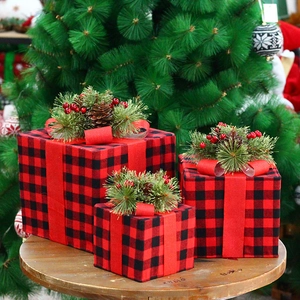 Trois boîtes cadeaux de Noël à carreaux rouges et noirs avec pommes de pin sous sapin