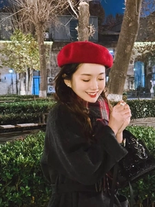 Winter look featuring a red wool beret with black wool coat and plaid scarf in a park