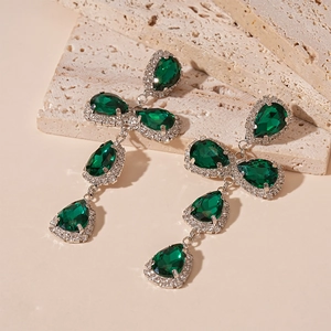 Detailed view of silver long drop earrings featuring green teardrop crystals and zircons