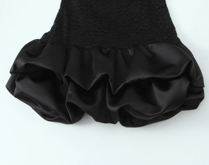 Close-up of black lace splicing and pleated satin hem on the short dress