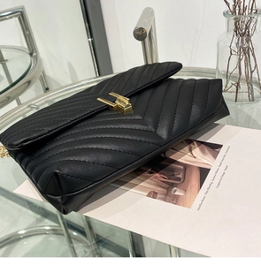 Detail view of black quilted leather handbag with gold metal clasp and accordion structure