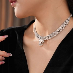 Detailed view of silver V-shaped necklace with teardrop pendant worn by a model