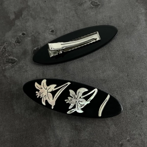 Detailed macro view of the vintage oval black resin hair clip with floral patterns