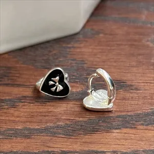 Detailed macro view of S925 sterling silver heart earrings with black enamel and bow