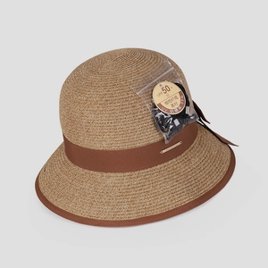 Detail of woven straw hat featuring UPF 50+ sun protection tag and elegant brown bow ribbon