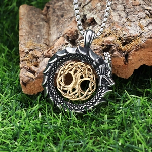 Detail of silver dragon and golden tree of life pendant on natural bark background