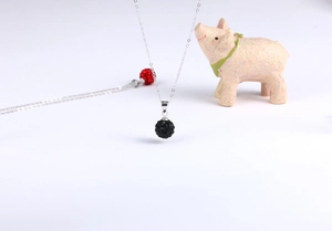 Detailansicht einer Silberkette mit einem schwarzen, funkelnden Kristall-Kugelanhänger