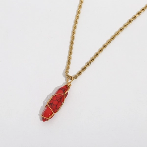 Detail of red turquoise stone pendant with golden wire wrapping on a rope chain