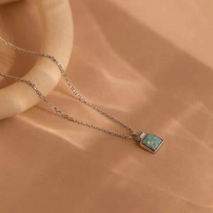 Detailed close-up of a square opal pendant on a silver-tone chain with vivid fire colors