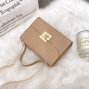 Detail of chevron embossed apricot crossbody bag with golden twist lock and chain strap