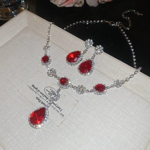 Dettaglio set collana e orecchini con rubino rosso a goccia e riflessi scintillanti