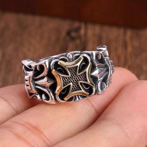 Detail of vintage gothic trident ring with golden cross engraving on silver band
