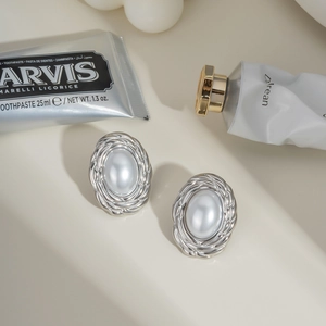 Detail of oval pearl stud earrings with silver twisted metal texture and vintage French style
