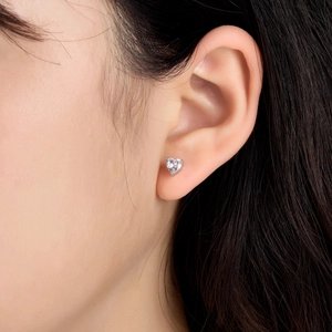 Elegant sterling silver heart-shaped zircon stud earrings worn by a model in a close-up shot