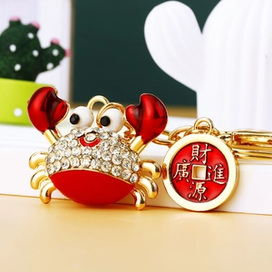Sparkling rhinestone crab keychain in gold and red with a lucky coin charm
