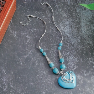 Detail view of bohemian heart turquoise pendant necklace on stone background
