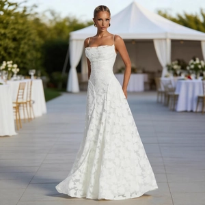 Elegant white floral lace spaghetti strap wedding dress in a scenic outdoor setting