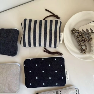 Overhead view of assorted mini canvas zipper pouches in denim, stripes, and polka dot patterns