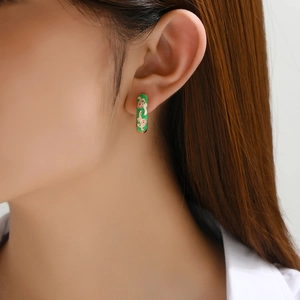Detail of vintage enamel floral hoop earring worn by a model in a close-up shot