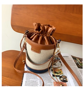 Detail of a vintage drawstring bucket bag with canvas stitching and brown leather trim
