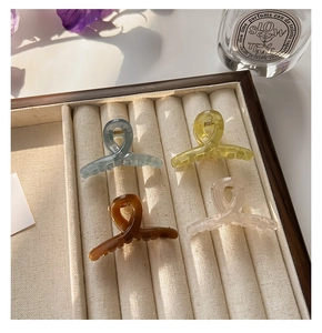 Close-up of four jelly-colored small hair claws in a velvet tray with natural lighting