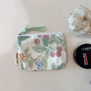 Detail of floral cotton zip pouch with green leaf print next to makeup accessories