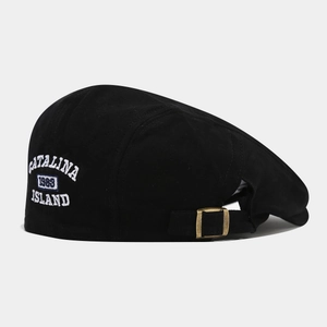 Détail de la casquette plate en coton noir avec boucle en métal et broderie blanche