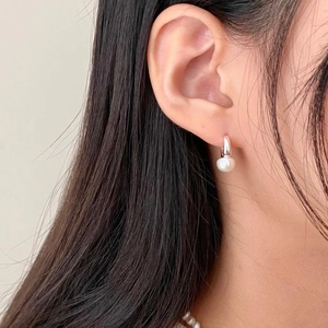 Close-up of elegant S925 silver hoop earrings with white pearls on a female model