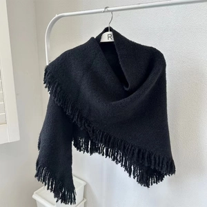 Detail showing the textured black knit fabric and tassel edges of the women's wool shawl