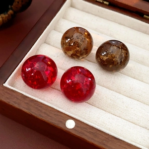 Macro shot of resin earrings with red ice-crack texture and golden foil inclusions