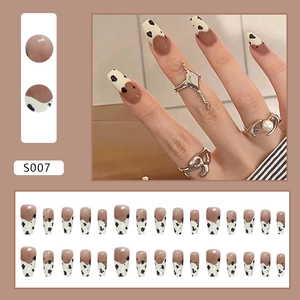 Minimalist medium ballerina fake nails with black and white cow print and nude brown base
