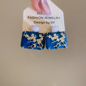 Detailed shot of blue enamel rectangular earring with golden plum blossom pattern