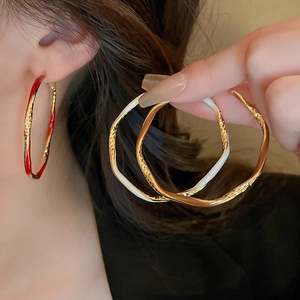 Detail of irregular hammered enamel hoop earrings showing texture and golden finish