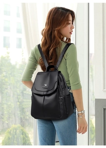 Close-up of a black leather backpack with a kangaroo metal logo on a female model