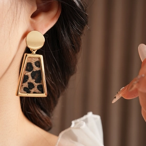 Gros plan de boucles d'oreilles dorées trapèze avec motif léopard sur un mannequin