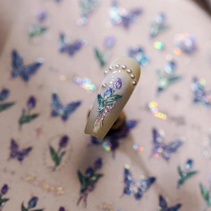 Macro shot of 3D nail art sticker featuring blue tulips and elegant white pearls