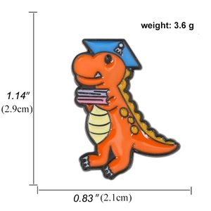 Cute orange dinosaur enamel pin with graduation cap and book, 1.14-inch badge accessory
