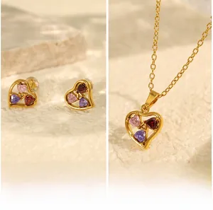 Detailed shot of golden heart jewelry set with pink, purple and red zircon stones