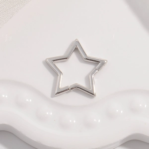 Macro shot of silver hollow star-shaped clasp jewelry accessory on ceramic surface