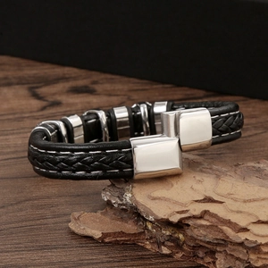 Handwoven black leather skull bracelet with silver magnetic clasp on natural bark