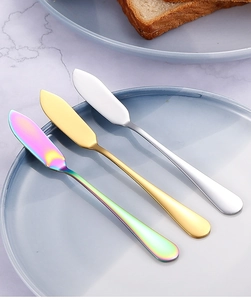 Gros plan de couteaux à beurre en acier inoxydable arc-en-ciel, or et argent sur une assiette