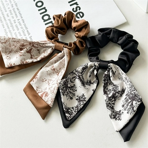 Detail of silk scrunchies with long ribbons in brown and black ink print patterns