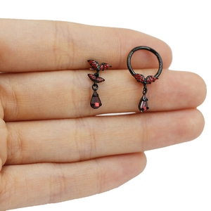 Macro shot of gothic black metal bat earrings with red drop pendant and bat patterns