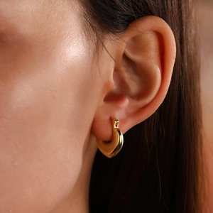 Detailed side view of a polished gold hollow heart-shaped earring on a female ear