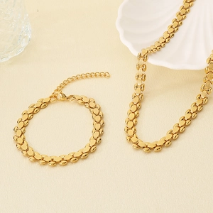 Detailed view of elegant gold-tone chain necklace and bracelet set on shell decor