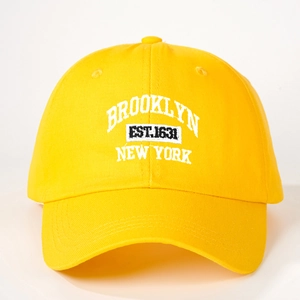 Detailed macro view of embroidered Brooklyn New York text on yellow cotton baseball cap