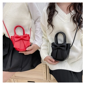 Detail of red and black PU leather handbags with decorative large bow and thin straps