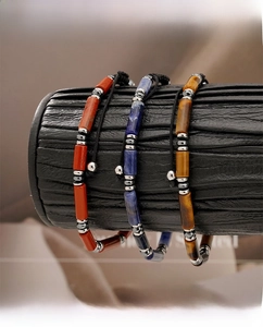 Detailed view of woven stone bracelets featuring tiger eye, red and blue natural beads
