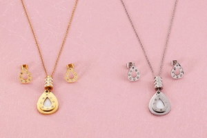 Flat lay of teardrop rhinestone necklace and earrings set in gold and silver finish